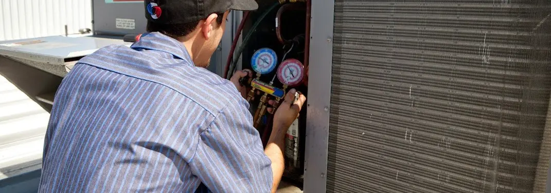HVAC technician servicing a condenser unit in Heber
